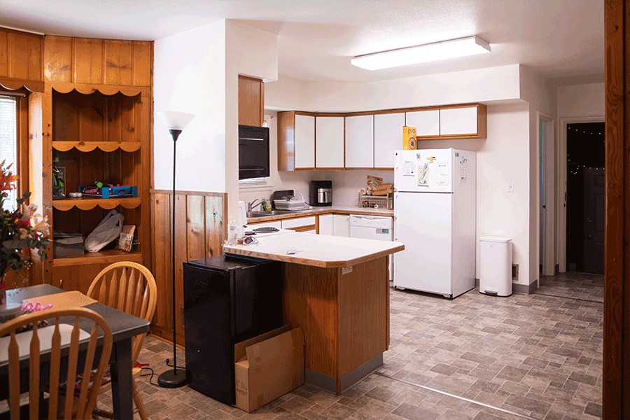 A bright kitchen and a paneled dining room with a peninsula counter in between.